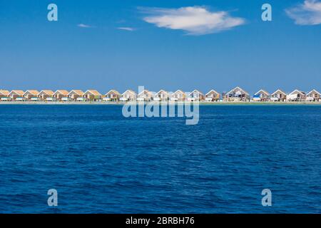 Landscape in Maldives Islands and over water villas and bungalows with group of dolphins swimming Stock Photo