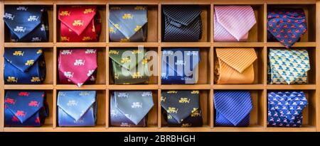 Showcase with multicolored ties. View of different colors ties in showcase. Multicolored man. Showcase of rolled neckties at store. Coiled ties on she Stock Photo