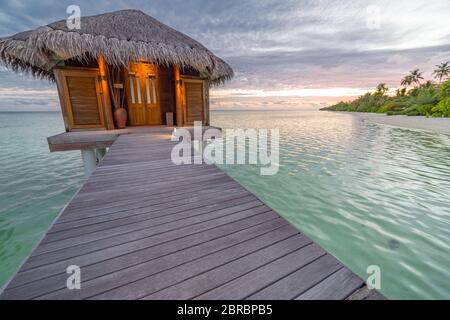 Beautiful isolated luxury water bungalows, sunset view Maldives in the blue green ocean of the Maldives. Luxury travel landscape Stock Photo