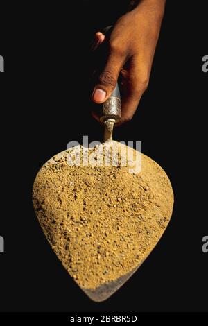 Trowel isolated on Black background. Sand and cement mixed on the trowel, Cement or mortar on the trowel in a hand.Cement Trowel Construction Tools, E Stock Photo