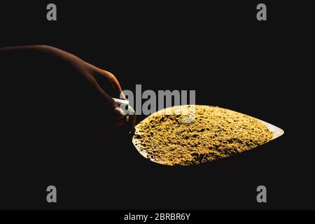 Trowel isolated on Black background. Sand and cement mixed on the trowel, Cement or mortar on the trowel in a hand.Cement Trowel Construction Tools, E Stock Photo