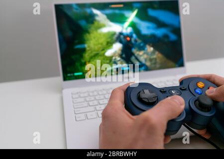 Playing game on laptop computer with joypad Stock Photo