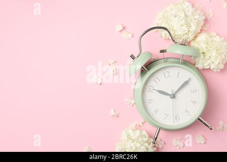 Alarm clock and beautiful hydrangea flowers on pink background Stock Photo