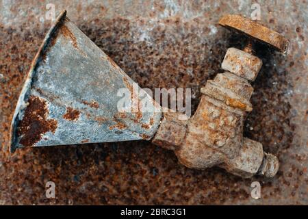 Rusty watering can with a crane lie on a rusty iron. Scrap metal. Close-up. Macro Stock Photo