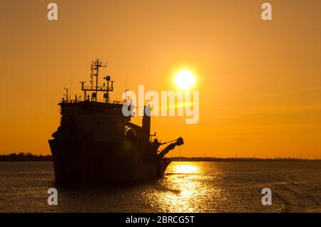 A work ship on the Elbe near Hamburg in the sunset Stock Photo