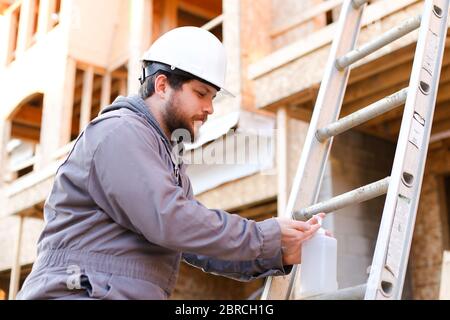 Young engineer using disinfectant soap on construction site. Stock Photo