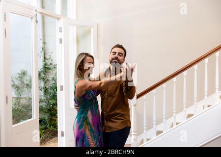 Caucasian couple having fun dancing and smiling in the hallway Stock Photo