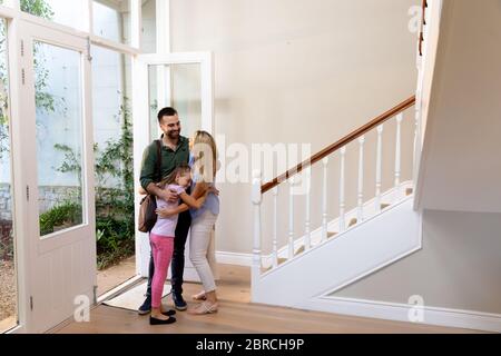 Caucasian couple and their daughter embracing in the hallway