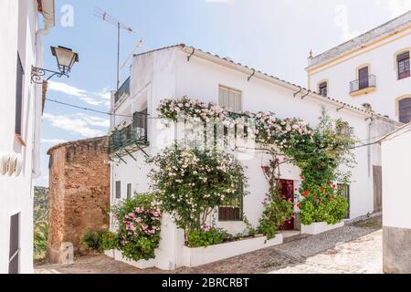 View of a beautiful white house with flowers in the facade in Zufre village, Sierra de Aracena, Huelva, Spain Stock Photo