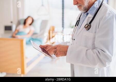 Unrecognizable doctor standing in hospital room, using tablet. Stock Photo
