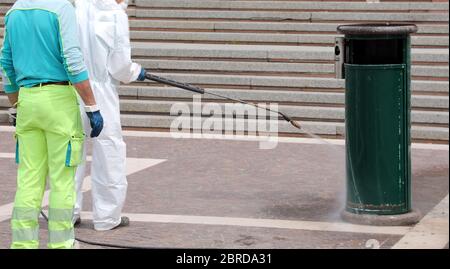 operating staff with protections during the disinfestation of city waste baskets Stock Photo