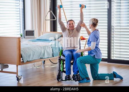 A healthcare worker and senior patient in hospital, physiotherapy. Stock Photo
