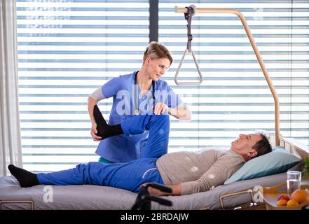 A healthcare worker and senior patient in hospital, physiotherapy. Stock Photo