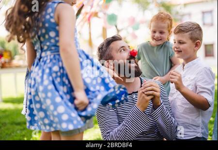 Man with small children sitting on ground outdoors in garden in summer, playing. Stock Photo