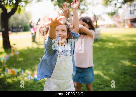 Small children standing outdoors in garden in summer, playing. Stock Photo