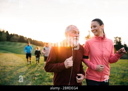 Large group of people cross country running in nature at sunset. Stock Photo