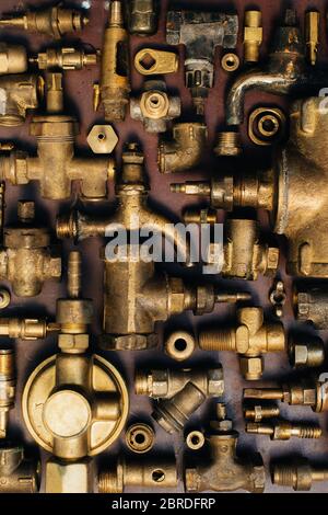 Brass scrap metal: taps, tees, plugs and various plumbing parts, spare parts. Against the background of a copper sheet. Close-up. Stock Photo