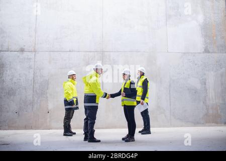 A group of engineers standing on construction site, shaking hands. Stock Photo