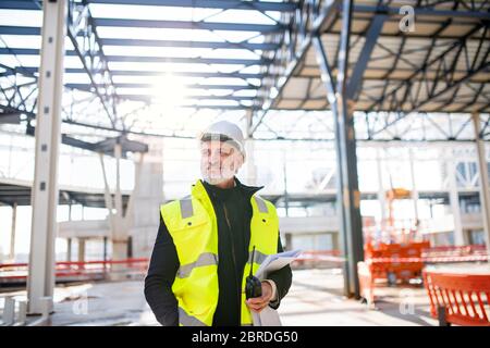 Man engineer with walkie talkie standing on construction site. Stock Photo