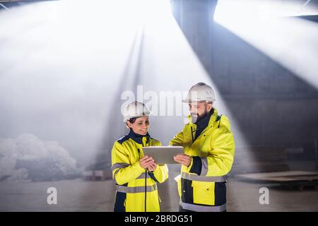 Engineers standing outdoors on construction site, holding tablet. Stock Photo