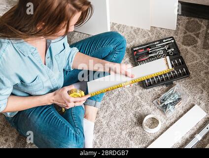 Young woman assembling new furniture for home Stock Photo