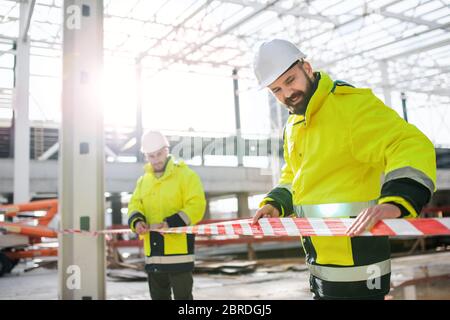 Men workers standing outdoors on construction site, working. Stock Photo