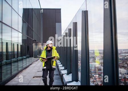 Man engineer walking on construction site, holding blueprints. Stock Photo