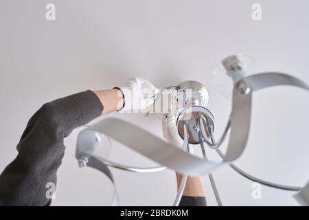 Installation ceiling lamp, hands of electrician fixing chandelier Stock Photo