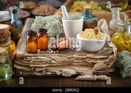 Bottles of homeopathic drugs, mortars of mineral substances and medicinal plants. Infusion bottles and healing herbs on background. Homeopathy medicin Stock Photo