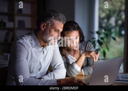 Architects with laptop sitting at the desk indoors in office, working late. Stock Photo