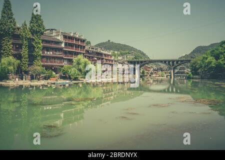 Feng Huang, China -  August 2019 : View of the road bridge over Tuo Jiang river and wooden houses in ancient old town of Fenghuang known as Phoenix Stock Photo