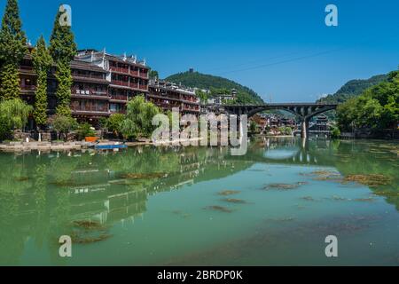 Feng Huang, China -  August 2019 : View of the road bridge over Tuo Jiang river and wooden houses in ancient old town of Fenghuang known as Phoenix Stock Photo