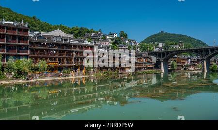 Feng Huang, China -  August 2019 : View of the road bridge over Tuo Jiang river and wooden houses in ancient old town of Fenghuang known as Phoenix Stock Photo