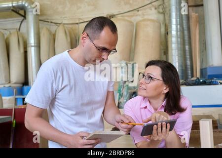 Male and female designers, carpenters, engineers working in an industrial workshop Stock Photo
