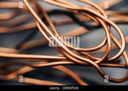 Copper scrap metal, wire, windings of motors and transformers, electrical wire without insulation. Against the background of a copper sheet. Close-up. Stock Photo