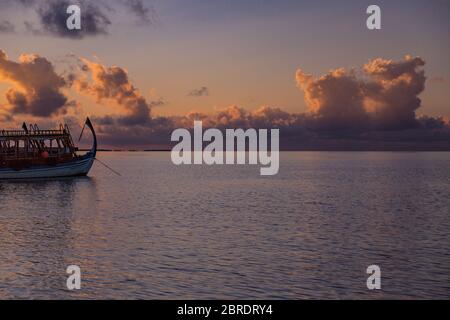 Maldives island sea sunset view with wooden boat Dhoni. Traditional Maldives sea Stock Photo