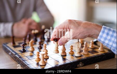 Midsection of senior men friends at home, playing chess. Stock Photo