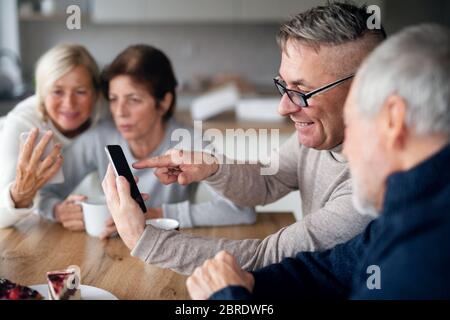Group of senior friends at home, using smartphones. Stock Photo
