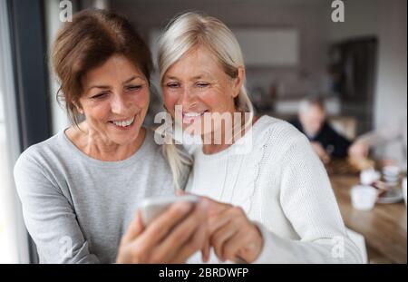 Group of senior friends at home, using smartphone. Stock Photo