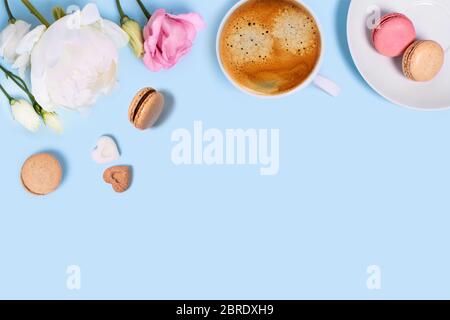 Blue background with cup of tasty coffee, macaroons, peonies and roses. Top view with space for your text. Stock Photo