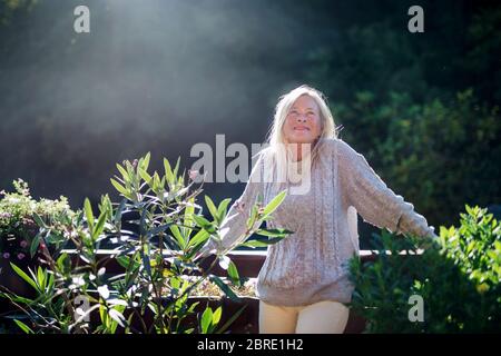 Senior woman standing outdoors on terrace, resting. Stock Photo