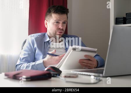 Young caucasian man working from home reading documents during isolation Stock Photo