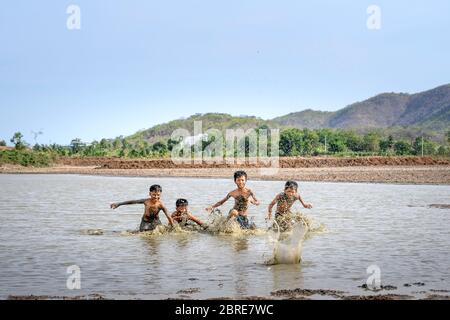 Phan Thiet, Binh Thuan Province, Vietnam - May 16, 2020: boys from a small village playing football in the mud, so happy and fun in Phan Thiet, Vietnam Stock Photo