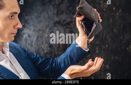 The man is holding an open empty brown leather wallet purse. The concept of economic crisis and business bankruptcy in the post-pandemic period Stock Photo