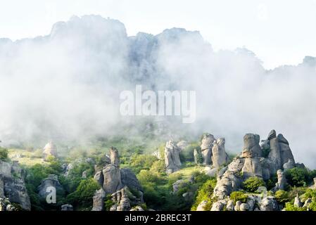 Misty mountain in Crimea, Russia. Scenic view of the Valley of Ghost. Scenery of bizarre foggy rocks in summer. Mountain landscape with low lying clou Stock Photo