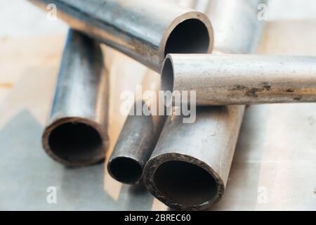 Stainless steel scrap metal, stainless steel pipes on the background of a stainless steel sheet. Close-up. Macro. Stock Photo