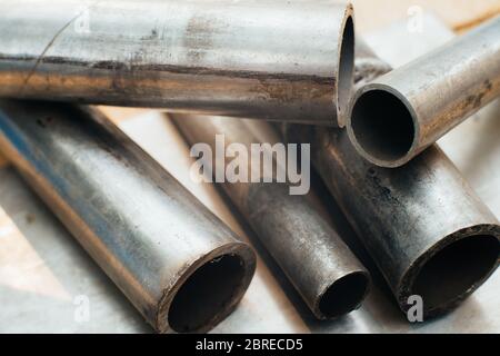 Stainless steel scrap metal, stainless steel pipes on the background of a stainless steel sheet. Close-up. Macro. Stock Photo