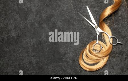 The hairdresser. Scissors and curl of hair on a black background. Stock Photo