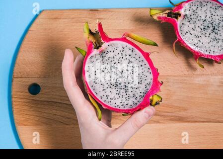 Dragon fruit in the hands of a girl. Slices of ripe pitaya on a blue background. Summer fruit. Pitaya species Hylocereus undatus. Healthy and healthy Stock Photo