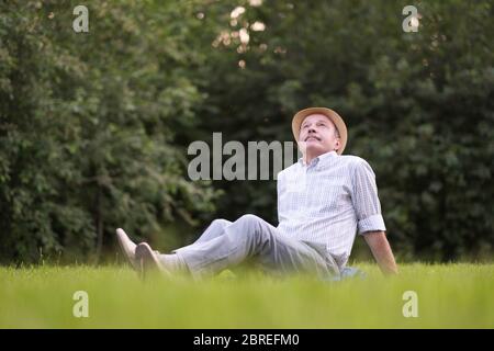Elderly spanish man resting, on fresh air lying on ground looking up. Stock Photo
